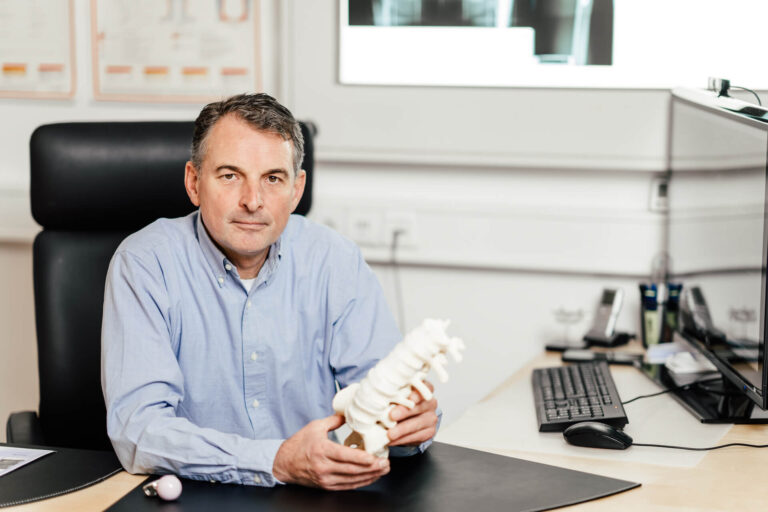 Dr. Roman Radl mit Wirbelsäulen Attrappe